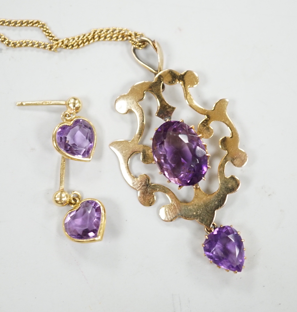 An early 20th century 9ct and two stone amethyst set drop pendant, 40mm, on a 9k chain, 60cm, gross weight 6.8 grams, together with a pair of 18ct gold and heart shaped amethyst set drop earrings, gross 1.6 grams.